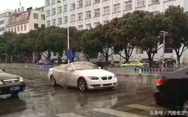 天上下着蒙蒙小雨，这宝马敞篷车挺有个性，披着1张破塑料纸就上路了