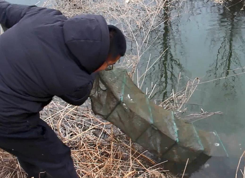 农村小伙在河里抓到一只小鱼,农村小伙河中发现废弃地笼