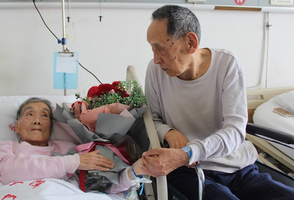 92岁老人坐轮椅在病房为89岁妻子送鲜花庆祝结婚65周年