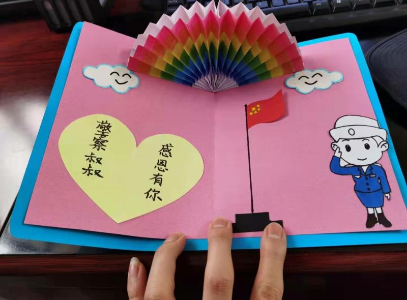 小朋友给00后民警送甜甜的锦旗图,民警小小锦旗表谢意
